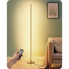 a person holding a cell phone in front of a floor lamp that is turned on