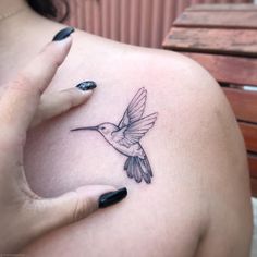 a woman's shoulder with a small tattoo of a hummingbird on her left arm