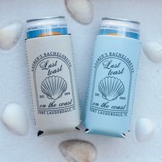 two can coolers sitting next to each other on top of a white table covered in shells