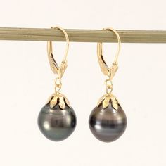 Brand New Solid Yellow Gold (not plated, not bonded) Tahitian Pearl Earrings Beautiful and unique well match dangle earrings. These Tahitian pearls finished with 14k solid yellow gold lever back and flower cap design. This genuine baroque Tahitian pearl earring is the epitome of natural beauty, grace. They are gaining popularity because of their unique look. The shimmering Tahitian pearl size is approximately width of 10.6mm. Due to their nature, no two pearls are alike, their nature making each pearl is one of kind. Therefore; we must send out exact pair on this listing if you purchase it. 1.Main Stone: Tahitian pearl 2.Color: Natural Black 3.Earring Size: approximately 10.6 mm width x 31mm length from bottom to the top (0.42 x 1.22 inches) 4.Earrings Total Weight: approximately 4.4 Grams Classic Tahitian Pearl Jewelry With Matching Earrings, Classic Tahitian Pearl Earrings As Gift, Classic Tahitian Pearl Earrings For Gift, Classic Tahitian Pearl Earrings For Anniversary, Tahitian Pearl Jewelry With Matching Earrings For Anniversary, Tahitian Pearl Jewelry With Matching Earrings For Gift, Tahitian Pearl Jewelry Set With Matching Earrings For Gift, Classic Tahitian Pearl Drop Jewelry, Classic Gold Tahitian Pearl Earrings