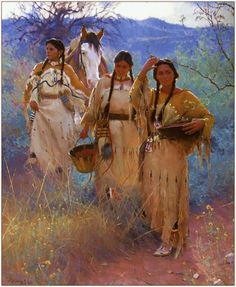 three women in native dress standing next to each other on a dirt road with horses behind them