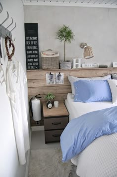 a bed with blue and white sheets in a bedroom next to a wooden headboard