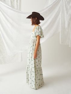 Embrace the countryside charm with our Anita Vintage Turquoise Dress by Madeline Marie. This maxi dress features a delicate floral print, puff sleeves, and a flattering empire waistline. The addition of a classic cowboy hat completes the look, perfect for casual outings and country-themed events. Summer Floral Print Prairie Dress With Puff Sleeves, Fitted Bohemian Puff Sleeve Dress With Gathered Sleeves, Fitted Bohemian Puff Sleeve Dress, Summer Prairie Dress With Empire Waist For Garden Party, Empire Waist Prairie Dress For Summer Garden Party, Puff Sleeve Empire Waist Dress For Garden Party, Spring Garden Party Prairie Dress With Empire Waist, White Prairie Dress With Fitted Bodice For Spring, Fitted Peasant Dress With Floral Print