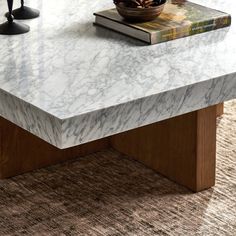 a marble coffee table with wooden legs and a book on it's end shelf