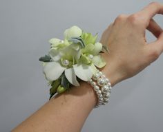 a woman's arm with a flower and pearl bracelet on top of her wrist