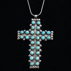 This is a stunning Vintage Native Zuni Turquoise Cross Pendant Necklace 26 Snake Eye Stones Sterling Silver 21g. This gorgeous LARGE handmade cross pendant necklace features 26 large snake eye turquoise stones that are sawtooth bezel set embellished with 34 raindrops. The 21 1/2" snake chain is hallmarked F.N.A./925/Italy. All the turquoise stones are in excellent condition with no cracks. There are matrix lines and one stone includes some pyrite. The cross was handmade by a skilled silversmith.  Condition: Excellent Vintage  Style: Cross Pendant Necklace Metal: 925 Sterling Silver (tested positive) Chain:  21 1/2" inches Pendant: 2 3/4" x 1 7/8"     Surface: Some patina/tarnish with slight polish Weight: 21 grams Hallmark: None- Unsigned  Tribal Affiliation:  Zuni #26629963 Handmade Turquoise Cross Pendant Necklace, Handmade Turquoise Cross Jewelry, Handmade Southwestern Cross Necklace, Southwestern Handmade Cross Necklace, Handmade Turquoise Cross Necklace, Turquoise Cross Pendant, Turquoise Cross, Turquoise Stones, Eye Stone