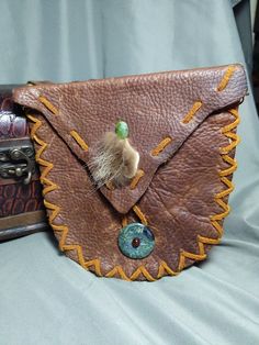 This is a small to medium sized leather belt pouch made from thick, upcycled leather and lacing. It has belt loop so you can wear it when and where you want. The inside features a smaller pocket good for change. It is also adorned with a small tuft of raccoon fur, serpentine, Jasper and Garnet. This pouch would work great as a alternative to a fanny pack or money pouch at events.  The pouch is 6 and 1/2 in across at the top and six and a half inches long in the middle. The belt loop is wide enou Everyday Hand-tooled Leather Pouch, Handmade Leather Belt Bag For Festival, Handmade Leather Pouch Belt Bag, Bohemian Leather Belt Bag For Everyday Use, Hand Tooled Brown Leather Pouch, Brown Leather Hand-tooled Pouch, Leather Hand-stitched Coin Purse For Everyday Use, Handmade Vintage Leather Pouch, Vintage Handmade Leather Pouch