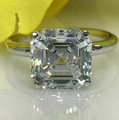 an engagement ring with a large diamond in the center and a yellow rose behind it