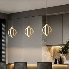 three lights hanging from the ceiling above a dining room table