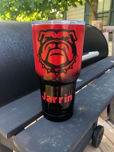 a red and black cup sitting on top of a bench