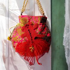 "Red Fish" is a small embroidered bag inspired by Japanese Hanfu fashion. Adorned with a magnificent goldfish adorned with jewels, this purse is made as a unique piece. Embroidered with flowers and pearls. The chain is made of gold beads and imitation mother-of-pearl. This pouch closes with sliding ties. Two pompoms with bells complete the original design of this bag. Bag for a boho wedding, for your evenings or your days, dare to wear it on all occasions. It can also be used as a jewelry or makeup bag. Dimensions: - 23X23 cm (add 5 cm for the total dimension with the fish tail) - 47 cm pearl chain Holds a medium sized cell phone and wallet. Ideal for making a unique and precious gift. Your grigri will be delivered directly from my hands to yours, with care and attention. - Maintenance tip Pink Bags For Evening And Festivals, Red Shoulder Bag For Festive Gift, Festive Red Shoulder Bag As Gift, Festive Red Shoulder Bag For Gifts, Red Shoulder Bag As Festival Gift, Red Shoulder Bag For Festivals And Gifts, Red Shoulder Bag For Festivals, Red Shoulder Bag For Festivals As Gift, Red Embroidered Potli Bag For Party