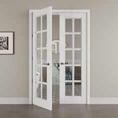 an empty room with two white doors and pictures on the wall behind them, in front of a framed photograph