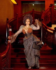 a woman is walking down the stairs in a dress and headdress with her arms outstretched