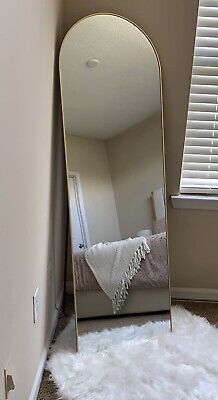 a large mirror sitting in the corner of a room next to a white sheepskin rug