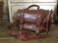 "Vintage Artisan Rustic Brown Leather Handbag Mini Briefcase ~~ c 1970s 2 side pockets with strap & buckle closures, 2 front strap and buckle closures. One pocket under the front flap. Silver hardware. Top leather carry handle that is studded in place. Adjustable and removable extra long carry strap to wear as a crossbody bag. Shoulder guard. Measures 12\" length, 14\" length including pockets, approx. 8\" height, approx. 6\" - 7\" depth including front pocket. Please check all measurements Retro Shoulder Bag With Hasp Closure For Travel, Vintage Leather Satchel Shaped As Standard Backpack, Vintage Bag With Flap And Detachable Strap, Leather School Bags With Buckle Closure, Leather School Bag With Buckle Closure, School Leather Bags With Buckle Closure, Satchel With Buckle Closure For Daily Use, Retro Canvas Satchel With Adjustable Strap, Vintage Flap Shoulder Bag For Everyday