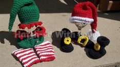 crocheted hats and boots are sitting on the ground next to an elf's hat