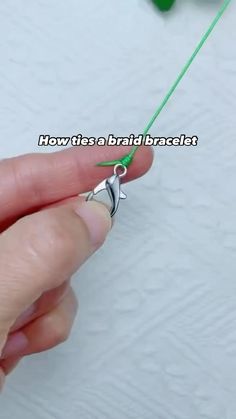 a person is holding a green string with a small white bird on it's end