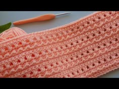 an orange crocheted sweater next to a pair of scissors and a green leaf