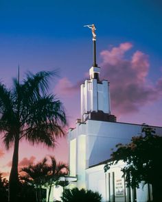 an image of a church with palm trees in the foreground and a sunset behind it