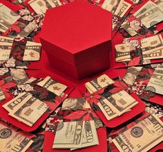 a red box sitting on top of lots of dollar bills in the middle of a pile