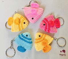 four crocheted fish keychains sitting on top of a white table next to each other