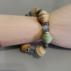 a woman's arm with two bracelets on it, one is made out of wood and the other has glass beads