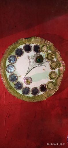 a paper plate with a peacock on it sitting on top of a red table cloth