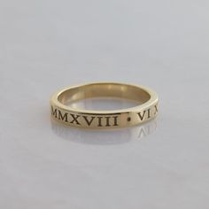 This is a personalized Roman Numeral band in solid 14K gold. The date of your choice is written in Roman Numerals twice around the ring(with a dot separator in between them) Features of the ring:   -Date of your choice is written twice around the band. Or instead, you can choose two  different dates.   -Font is Times New Roman, which is cast right into the ring to give the letters plenty of depth   -Band is 3mm wide and 1.5mm thick.    -Made to order in your size.  - Arrives in a rectangular bla Personalized Engraved 14k Gold Ring, Gold Timeless Stackable Rings For Promise, Timeless Gold Stackable Promise Rings, Timeless Gold Stackable Rings For Promise, Heirloom Rose Gold Stackable Rings Stamped 14k, Heirloom Yellow Gold Engraved Stackable Rings, Heirloom Engraved Yellow Gold Stackable Rings, 14k Yellow Gold Engraved Bands, Engraved 14k Yellow Gold Bands