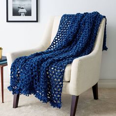 a blue crocheted afghan sitting on top of a chair in a living room