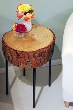 a vase with flowers sitting on top of a wooden table next to a white chair