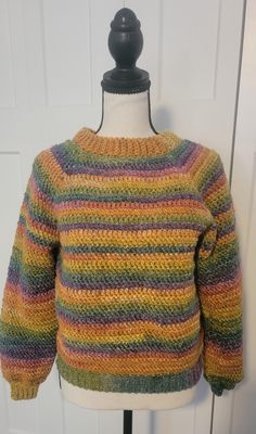 a knitted sweater with multicolored stripes on the front and back, sitting on a mannequin's head