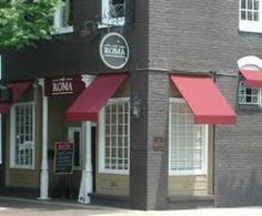 a restaurant with red awnings on the side of it's front door