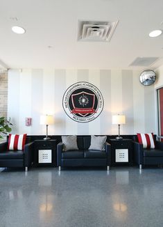 a large room with couches and lamps on the wall, in front of a circular emblem