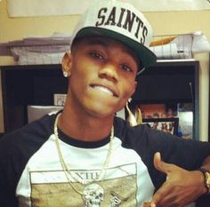 a young man wearing a saints t - shirt and a baseball cap is giving the thumbs up