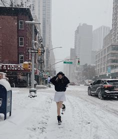 a woman walking down a snow covered street