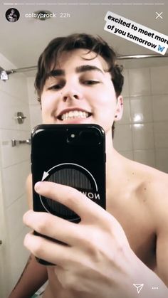 a young man taking a selfie in the mirror with his cell phone and smiling