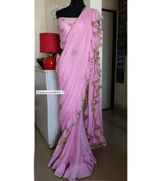 Color : Pink Fabric - Chinon This Ruffled Saree has beautiful Crystal Scallop trim at the hemline. Length of Saree 48 inches. Blouse : Pink Emroidered Net with Silk Lining The blouse and underskirt/petticoat will be stitched as per the measurements provided IF YOU WISH TO PURCHASE THIS WE CAN SEND A VIDEO ON YOUR WHATSAPP NUMBER FOR BETTER UNDERSTANDING OF THE SAREE Fabric Care : Dry Clean Only Disclaimer: The actual color of the product might slightly differ from the image due to photographic l Wedding Blouse Piece With Ruffles, Pink Georgette Pre-draped Saree With Embroidered Border, Reception Saree With Embroidered Border In Pink, Fitted Pre-draped Saree With Embroidered Border For Reception, Traditional Drape Wedding Wear With Ruffles, Traditional Wedding Wear With Ruffles And Traditional Drape, Fitted Tissue Silk Saree With Gota Work, Fitted Tissue Silk Pre-draped Saree With Gota Work, Traditional Drape Wear With Ruffles For Festivals