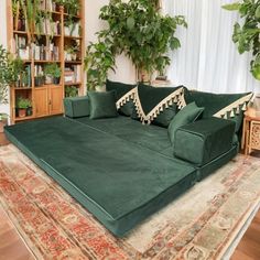 a large green couch sitting on top of a rug in front of a book shelf