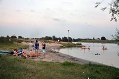 people are gathered at the edge of a body of water