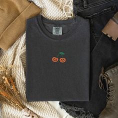 If you love Halloween & nostalgia - you NEED this Embroidered Pumpkin Cherry Comfort Colors T-Shirt! This is perfect for the fall season- would also make a great gift for someone that is obsessed with all things Halloween/Fall. * PRODUCT DETAILS * ✺ 100% Cotton ✺ Wash and dry normally (on cool for best results) ✺ Due to different monitor screens, colors may vary ✺ * SIZING * ✺ FOR AN OVERSIZED FIT, SELECT TWO OR THREE SIZES UP FROM YOUR NORMAL SIZE ✺ ✺ Sizing is unisex ✺ Size guide: Please consu Black Embroidered T-shirt For Fall, Black Embroidered Tops For Halloween, Halloween Embroidered Streetwear Top, Halloween Streetwear Embroidered Top, Embroidered Black T-shirt For Fall, Halloween Cotton Top With Embroidered Graphics, Halloween Embroidered Cotton Tops, Halloween Cotton Embroidered Tops, Embroidered Cotton Tops For Halloween