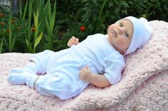 a baby laying on top of a pink blanket next to some grass and flowers in the background