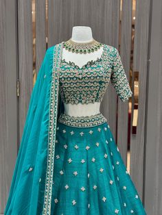 Teal green lehenga beautified in flora gold zari embroidery with sequin, aari tari, cut dana and pearl work all over. Completed look with similarly embroidered cut work blouse with lace border work dupatta. Embrace the whims of rich heritage by adorning this Teal green lehenga. Fabric: Raw Silk Size: 38/M Occasion: Wedding Ceremony or Reception WASH CARE INSTRUCTIONS - Please Dry clean only when it is applicable. Slight color variation is possible due to digital photography. Ready to Ship! Green Embroidered Tissue Silk Sets, Raw Silk Sharara With Zari Work For Reception, Reception Sharara With Zari Work, Wedding Lehenga With Dabka Work In Raw Silk, Pista Green Raw Silk Sharara For Reception, Green Chanderi Set For Reception, Green Embroidered Dress In Tissue Silk, Green Embroidered Tissue Silk Dress, Embroidered Green Dress In Tissue Silk