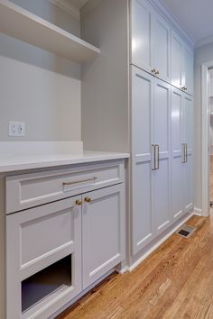 an empty kitchen with white cabinets and wood flooring in the middle of the room