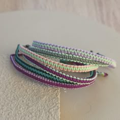 three different colored bracelets sitting on top of a white cloth covered table next to a wall