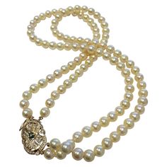 This timeless double strand pearl necklace exudes elegance and sophistication. Composed of two strands of well-matched light golden cultured pearls, each measuring 7 to 7.3 mm, the necklace offers a beautiful luster and refined appeal. The piece is completed with a stunning 14-karat yellow gold and diamond clasp, which features a square-shaped emerald of approximately 0.30 carats, flanked by diamonds totaling approximately 1.50 carats. At 16 inches in length, this necklace is the perfect complem Vintage Gold Akoya Pearl Necklace, Formal Double Strand Pearl Necklace With Pendant, Classic Double Strand Pearl Pendant Necklace, Classic Double Strand Pearl Necklace With Pendant, Gold Double Strand Pearl Necklace For Formal Occasions, Formal Gold Double Strand Pearl Necklace, Vintage Double Strand Pearl Necklace For Anniversary, Double Strand Pearl Necklace, Jewellery Indian