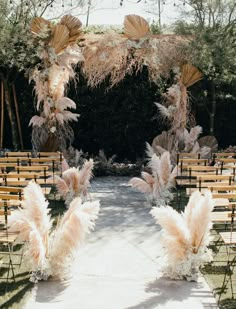 an outdoor ceremony setup with chairs and pamolite flowers on the aisle, surrounded by trees