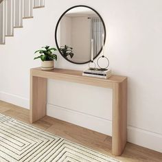 a wooden table with a mirror on it next to a stair case and potted plant