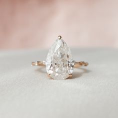 a pear shaped diamond engagement ring on a white surface