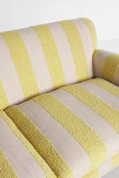 a yellow and white striped couch sitting on top of a table