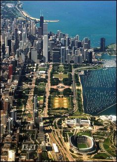 an aerial view of a large city with lots of tall buildings and water in the background